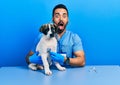 Handsome hispanic veterinary man with beard checking dog health using stethoscope afraid and shocked with surprise and amazed Royalty Free Stock Photo
