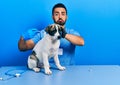Handsome hispanic veterinary man with beard putting vaccine to puppy dog depressed and worry for distress, crying angry and afraid Royalty Free Stock Photo