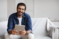 Handsome Indian Guy With Digital Tablet Computer Sitting On Couch At Home Royalty Free Stock Photo