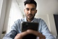 Handsome Indian guy using smartphone at home, close up shot Royalty Free Stock Photo