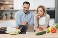 Handsome indian man and caucasian blond woman using laptop searching recipes Royalty Free Stock Photo