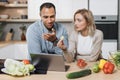 Handsome indian man and caucasian blond woman using laptop searching recipes Royalty Free Stock Photo