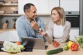 Handsome indian man and caucasian blond woman using laptop searching recipes Royalty Free Stock Photo