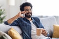 Handsome Indian Man Talking On Mobile Phone And Drinking Coffee At Home, Royalty Free Stock Photo