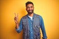 Handsome indian technician man wearing uniform over isolated yellow background smiling with happy face winking at the camera doing Royalty Free Stock Photo