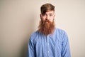 Handsome Irish redhead business man with beard standing over isolated background with serious expression on face Royalty Free Stock Photo