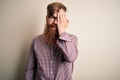 Handsome Irish redhead business man with beard wearing glasses over isolated background covering one eye with hand, confident Royalty Free Stock Photo