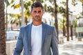 Handsome italian man walking on the city street wearing elegant fashionable suit, looking at camera Royalty Free Stock Photo