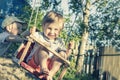 A handsome joyful boy of 2 years old is swinging on a swing and smiling. The older brother pushes the swing in which the younger b Royalty Free Stock Photo