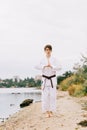 Beautiful boy in white karate kimono on the beach background. Judo practice concept. Copy space. Royalty Free Stock Photo