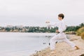 Beautiful boy in white karate kimono on the beach background. Judo practice concept. Copy space. Royalty Free Stock Photo