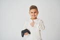 Handsome kid with gamepad on white background. Handsome boy gamer thumbs up and smile.