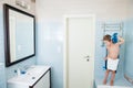 Handsome kid is wiped with a towel standing in bright blue bathroom