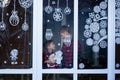 Handsome Kids standing by the decorated window with a toy santa claus and look and wait Christmas eve. Children hug and enjoy the Royalty Free Stock Photo