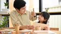 Handsome Asian male art teacher giving a thumbs up to his adorable young student Royalty Free Stock Photo