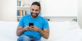 Handsome latin american hipster man with beard sending message at mobile phone Royalty Free Stock Photo