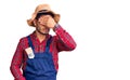 Handsome latin american young man weaing handyman uniform covering eyes with hand, looking serious and sad