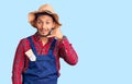 Handsome latin american young man weaing handyman uniform smiling doing phone gesture with hand and fingers like talking on the Royalty Free Stock Photo