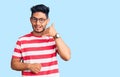 Handsome latin american young man wearing casual clothes and glasses smiling doing phone gesture with hand and fingers like Royalty Free Stock Photo