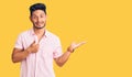 Handsome latin american young man wearing casual summer shirt showing palm hand and doing ok gesture with thumbs up, smiling happy Royalty Free Stock Photo