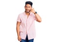 Handsome latin american young man wearing casual summer shirt smiling doing phone gesture with hand and fingers like talking on Royalty Free Stock Photo