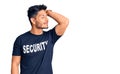 Handsome latin american young man wearing security t shirt smiling confident touching hair with hand up gesture, posing attractive Royalty Free Stock Photo