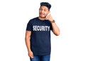 Handsome latin american young man wearing security t shirt smiling doing phone gesture with hand and fingers like talking on the Royalty Free Stock Photo