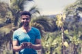 Handsome Latin Man Messaging With Cell Smart Phone Over Tropical Forest Background, Portrait Of Young Guy Chatting Royalty Free Stock Photo