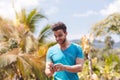 Handsome Latin Man Messaging With Cell Smart Phone Over Tropical Forest Background, Portrait Of Young Guy Chatting Royalty Free Stock Photo