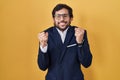 Handsome latin man standing over yellow background excited for success with arms raised and eyes closed celebrating victory Royalty Free Stock Photo