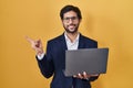 Handsome latin man working using computer laptop with a big smile on face, pointing with hand finger to the side looking at the Royalty Free Stock Photo