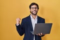 Handsome latin man working using computer laptop very happy and excited doing winner gesture with arms raised, smiling and Royalty Free Stock Photo