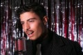 Handsome latino singer performs in front of vintage microphone in nightclub