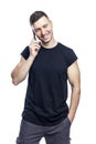 A handsome laughing man in a black t-shirt is talking on the phone. Career, business and success. Isolated on white background. Royalty Free Stock Photo