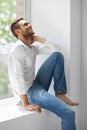 Handsome laughing man relaxing on window sill