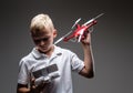 Handsome little boy boxer with blonde hair dressed in a white t-shirt holds a quadcopter and control remote.