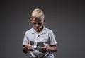 Handsome little boy boxer with blonde hair dressed in a white t-shirt holds a quadcopter control remote.