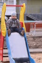 Handsome little boy in grey sits in slide