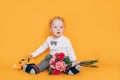 Handsome little boy holding flowers in his hands in front of yellow background in white shirt and bow tie. Taking care of children Royalty Free Stock Photo