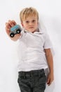 An handsome little child boy lying on the floor on his back holding up a wooden car toy