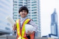 Handsome little engineer asian boy holding safety helmet and blueprint. Adorable little smart kid wear protective workwear and Royalty Free Stock Photo