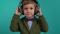 Handsome little toddler boy listening to music with old headphones, child having fun, funny dancing in studio on blue