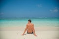 Handsome lonely sexy model looking man sitting at the beach with palm trees at the tropical island luxury resort Royalty Free Stock Photo