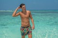 Handsome lonely tanned sexy model looking man sitting at the beach with palm trees at the tropical island luxury resort Royalty Free Stock Photo