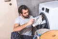 handsome loner looking at cloth from washing machine Royalty Free Stock Photo