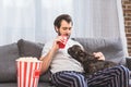 handsome loner palming dog and drinking beverage on sofa in living Royalty Free Stock Photo