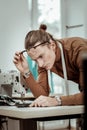 Handsome long-haired fashion dressmaker in eyeglasses looking serious