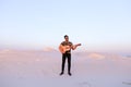 Handsome male Arab playing guitar standing in middle of bottomle