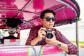 Handsome male Asian tourist holding camera on tuk tuk taxi in Bangkok Thailand Royalty Free Stock Photo