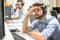 Handsome male Call center operator with headset suffering from headache staring at computer screen Royalty Free Stock Photo